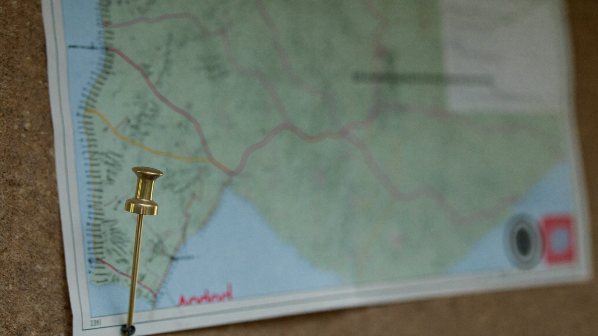 A land-use map thrown far out of focus with a single brass pushpin in sharp focus