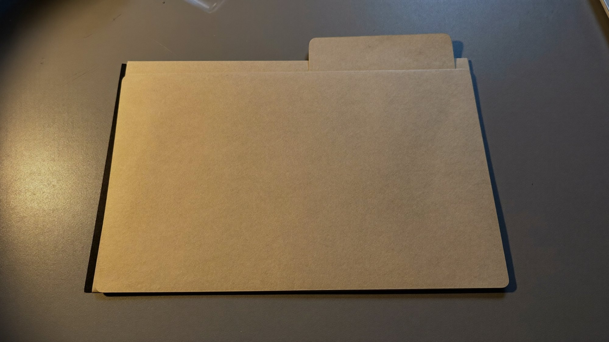 A closed buff document folder squared on a grey desk