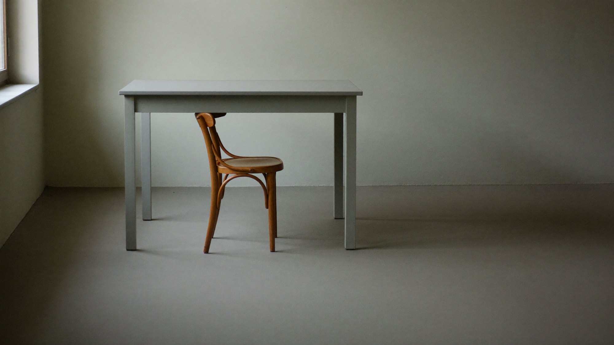An empty chair at a bare table in an empty room