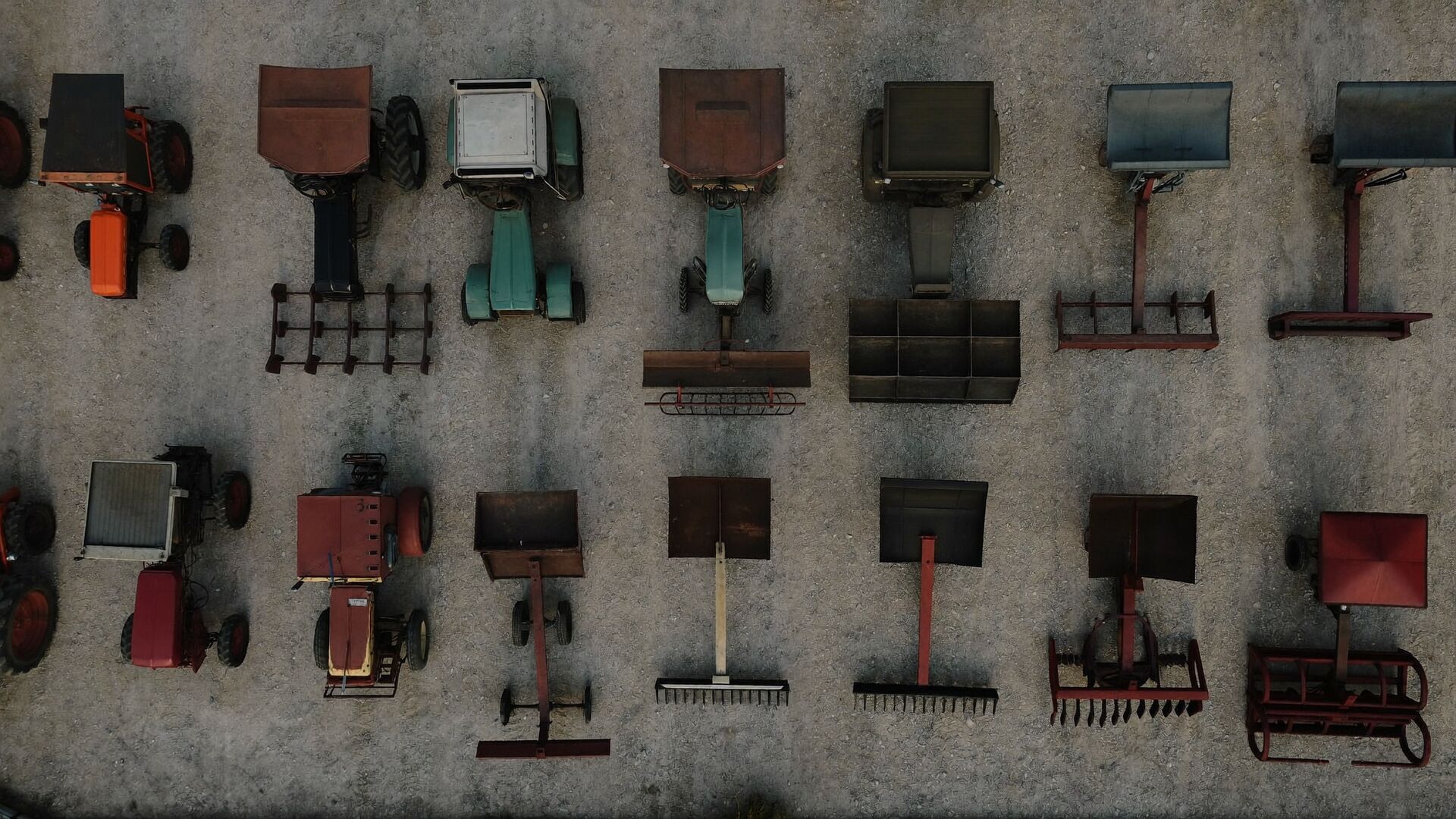 Overhead view of rows of tractors and farm implements parked in an equipment yard