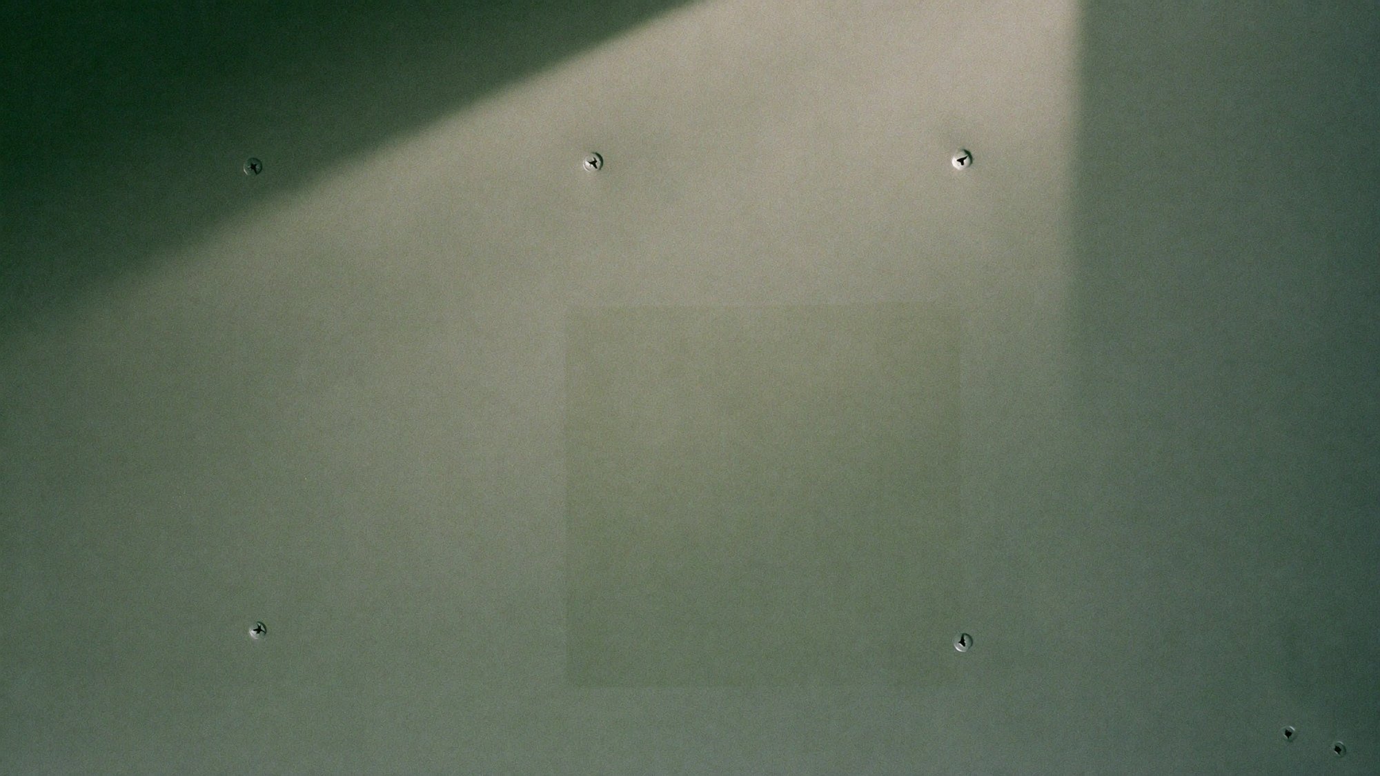 A pale rectangle on an institutional wall where a sign has been removed