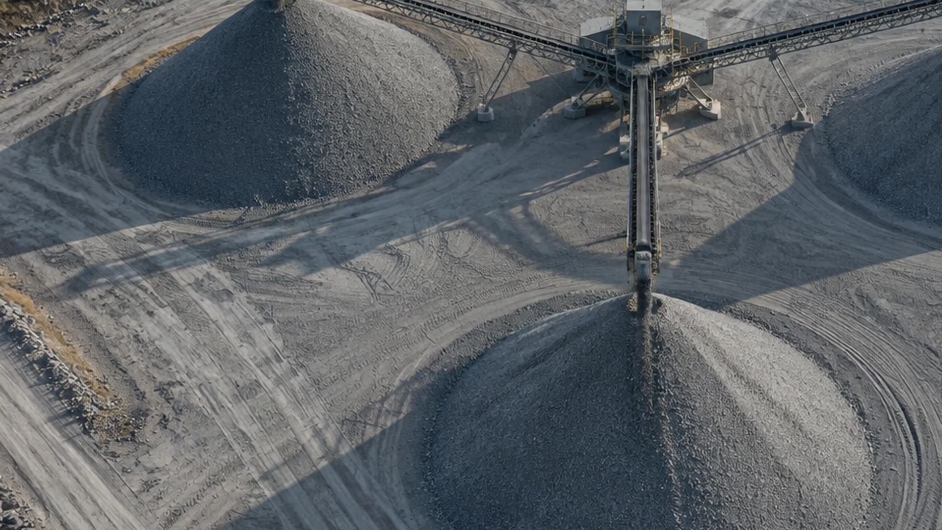 Aerial view of conical aggregate stockpiles fed by a radial stacking conveyor