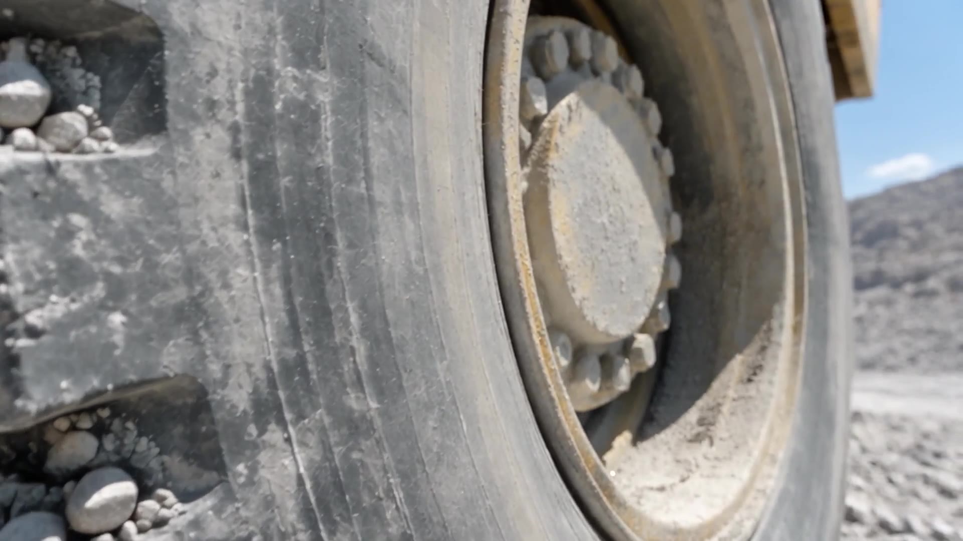 Close view of crushed stone moving along a conveyor belt over a return roller