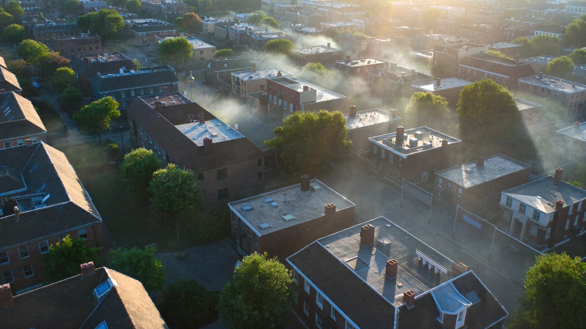 A small city at dawn with a water tower rising above the rooftops